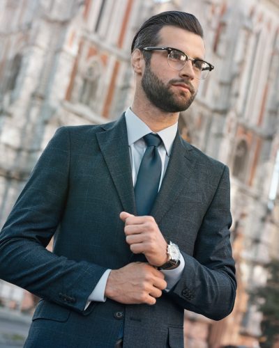 Close up profile portrait of a successful young bearded guy in suit and glasses. So stylish and